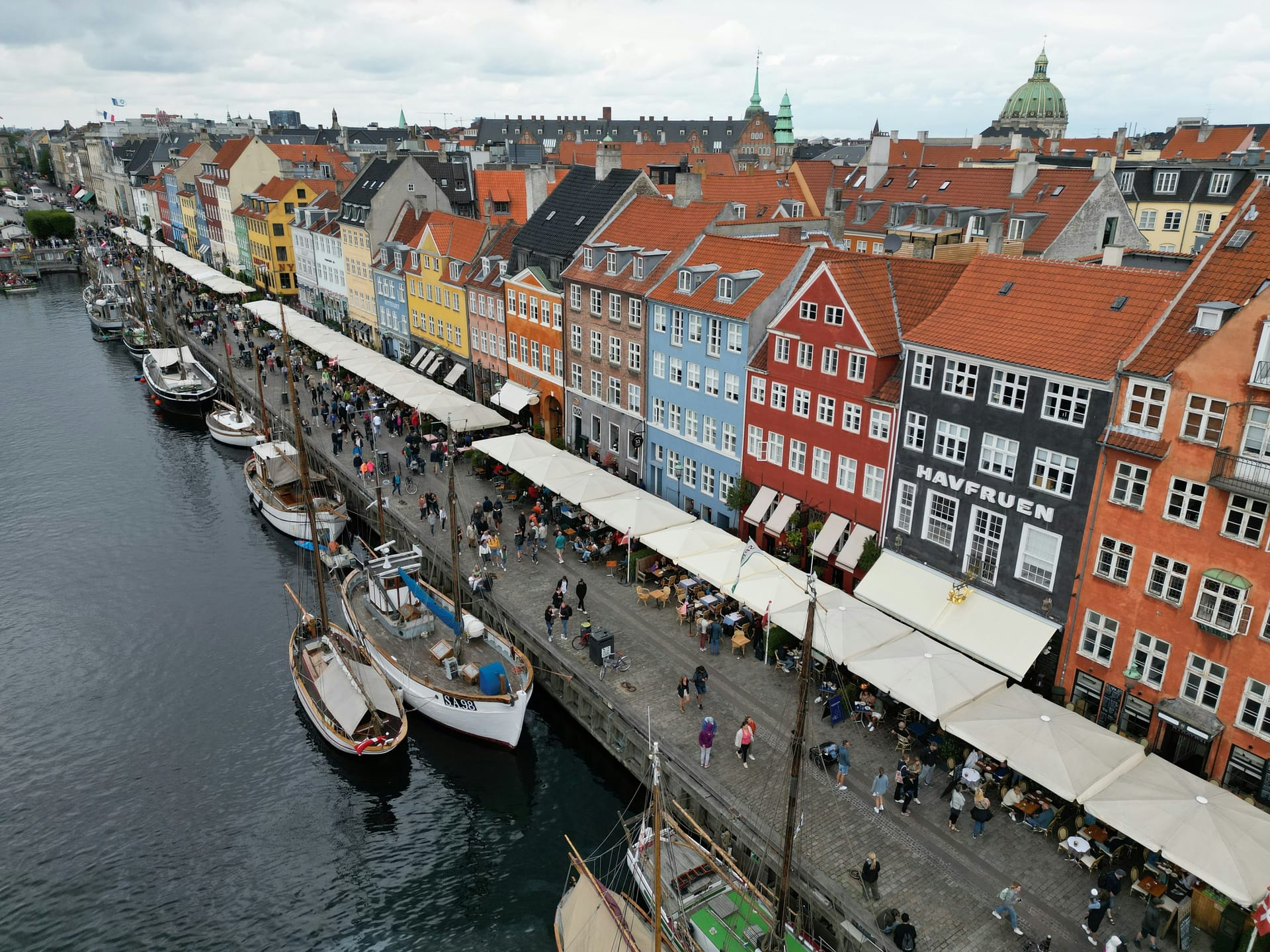 The colourful 17th-century waterfront townhouses of Nyhavn in Copenhagen with wooden sailing boats moored along the canal