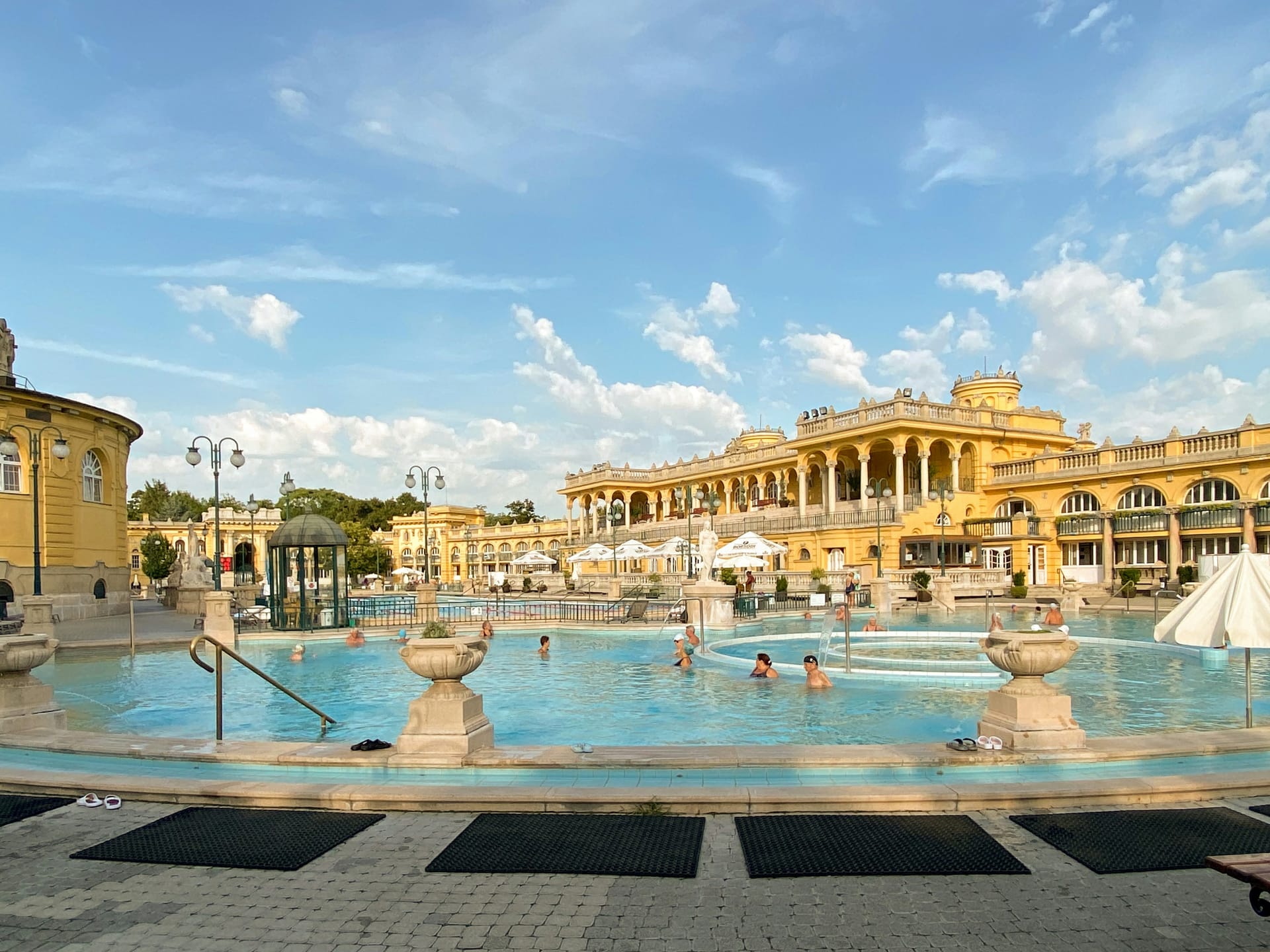 Bathers relaxing in the steaming outdoor pools of Széchenyi Thermal Bath, surrounded by the yellow neo-baroque facade
