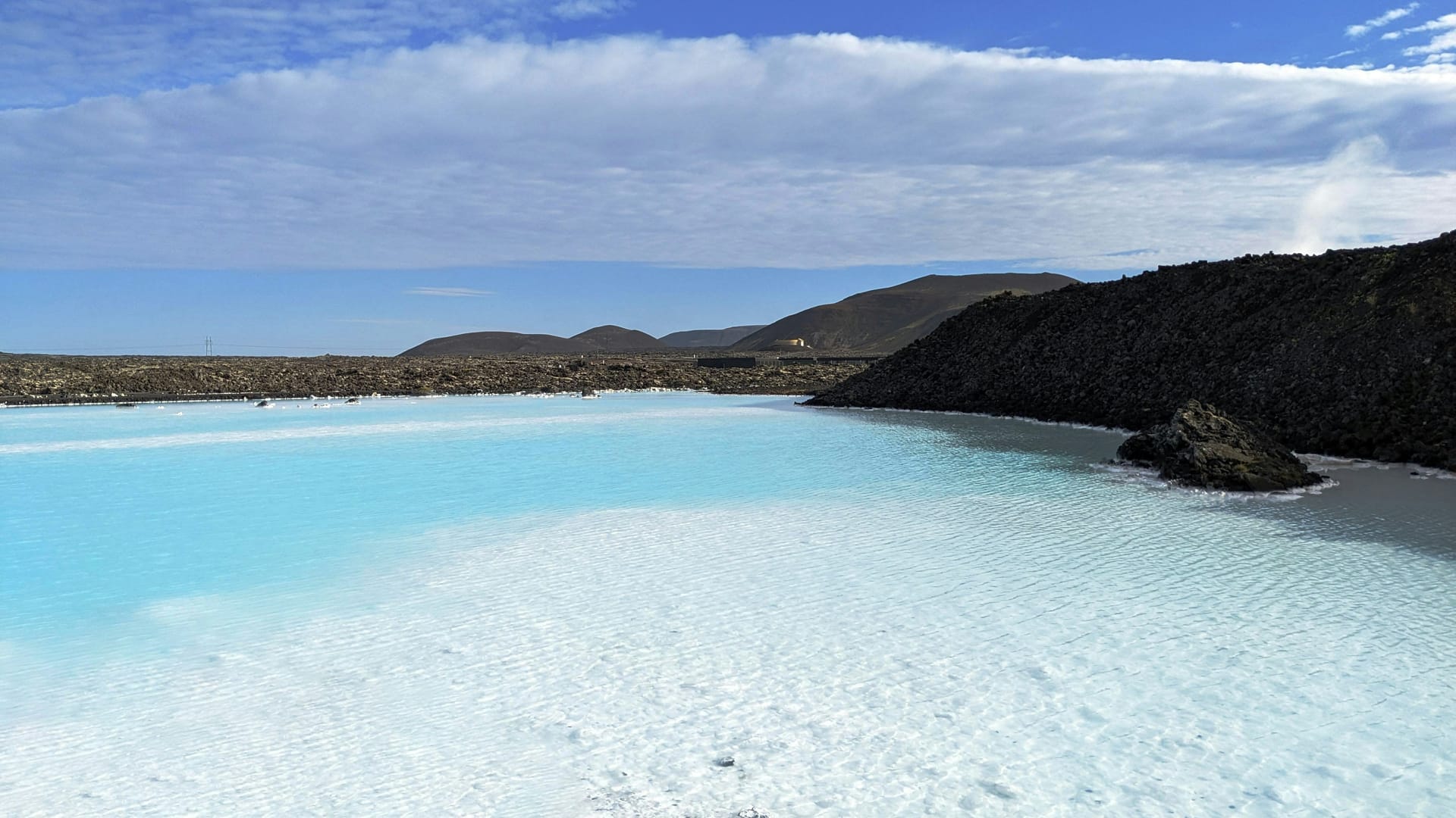 The milky blue waters of the Blue Lagoon geothermal spa in Iceland with a person bathing